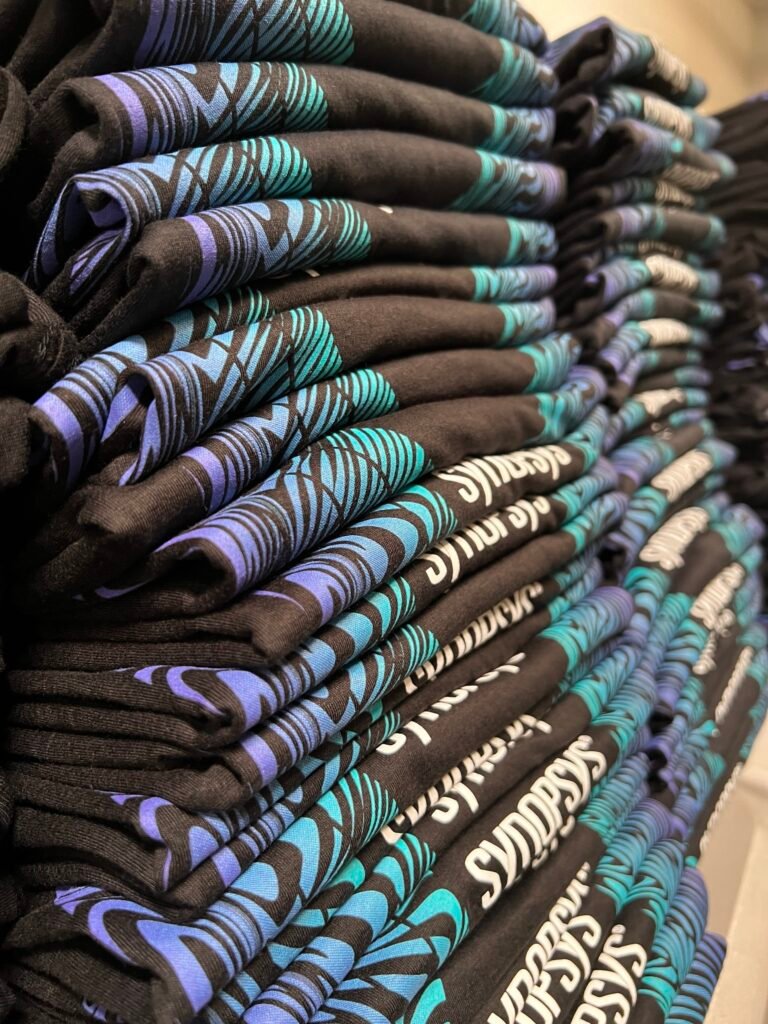 Stack of folded black t-shirts screen printed with a multi-color design in Phoenix, Arizona