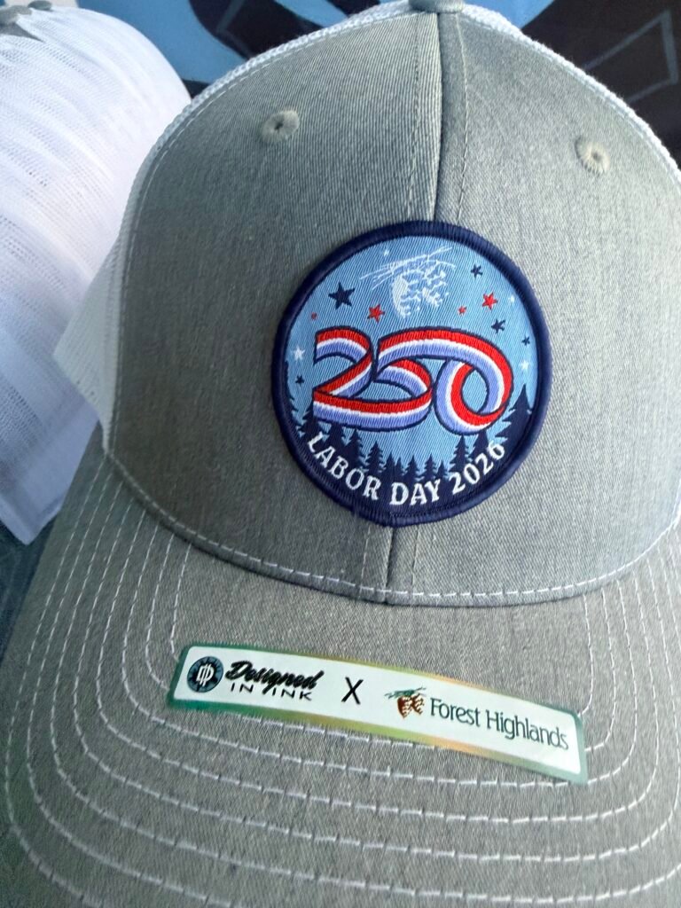 Grey and white trucker hat with a custom round embroidered patch, decorated by Designed In Ink in Phoenix Arizona