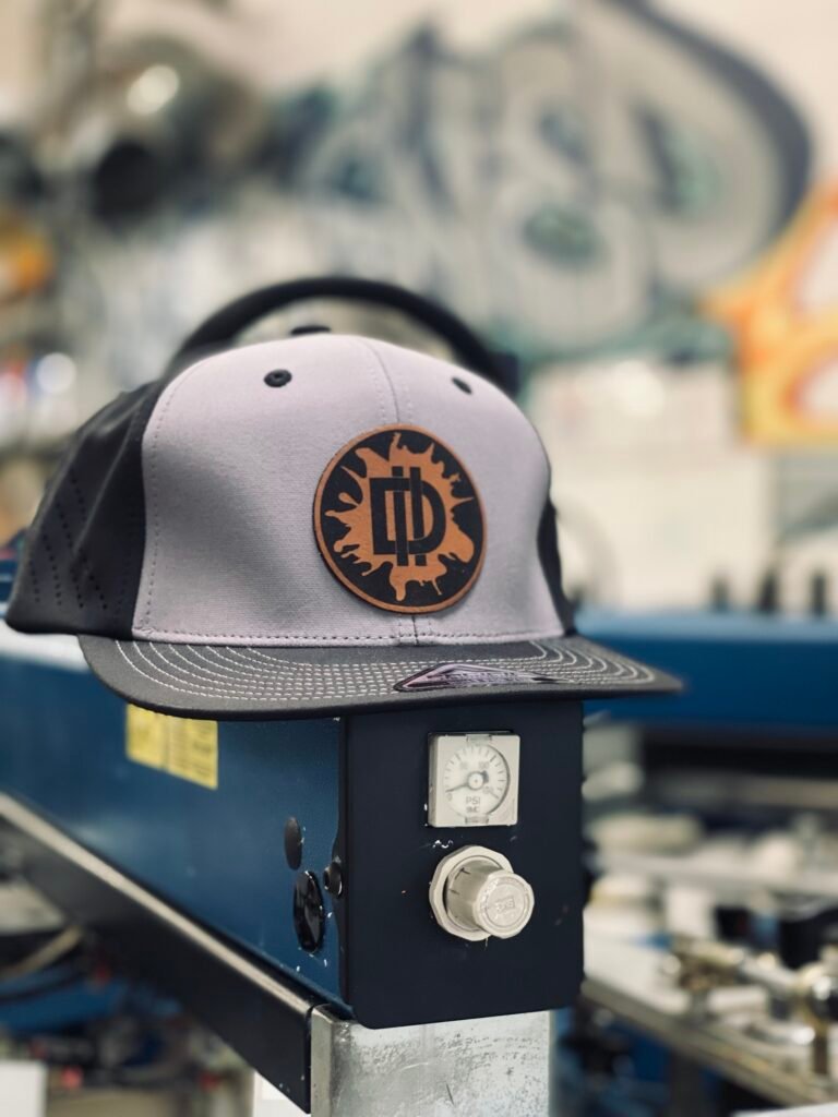 Custom cap on a screen printing press in the Designed In Ink shop in Phoenix