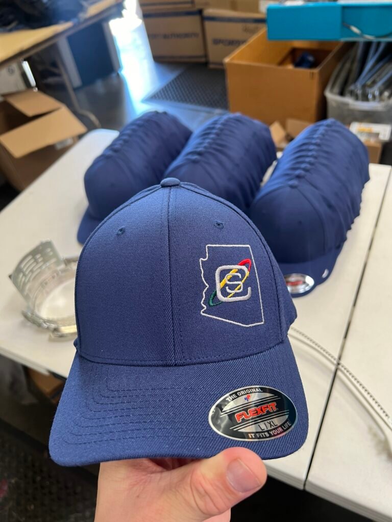 Navy fitted Flexfit cap with an embroidered Arizona state outline logo, part of a bulk order embroidered in Phoenix Arizona