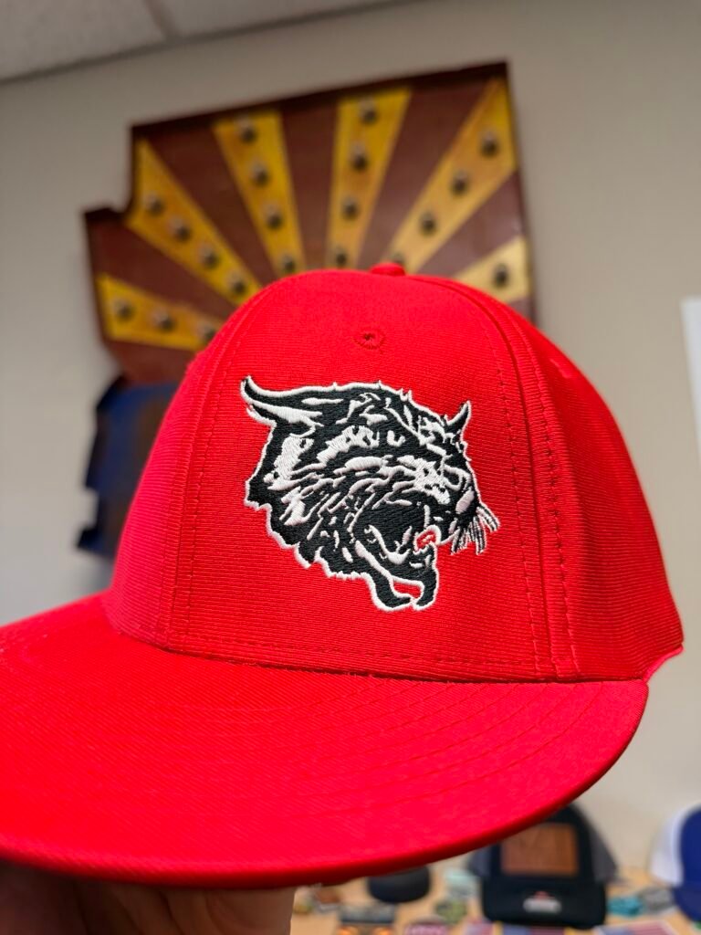 Red fitted cap with a detailed black and white embroidered mascot logo, stitched in Phoenix Arizona
