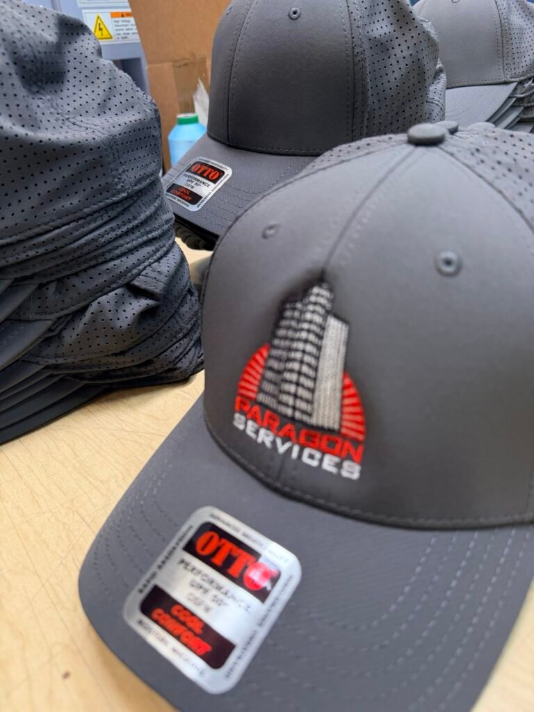 Stack of grey perforated performance caps embroidered with a company logo in Phoenix Arizona