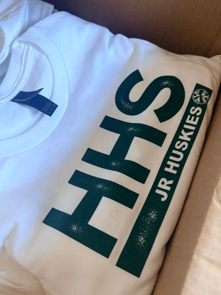 White school spirit t-shirt screen printed with a large green team graphic, printed in Phoenix Arizona